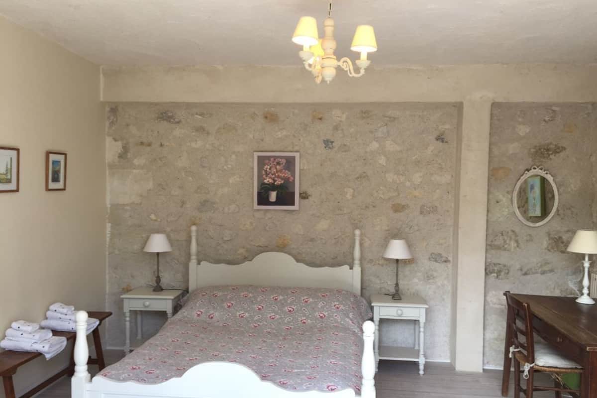 A bedroom with a bed, two bedside tables, a chair, and a small table.