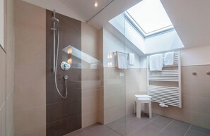 Superior appartement | Badkamer | Een douche, een haardroger, handdoeken, zeep