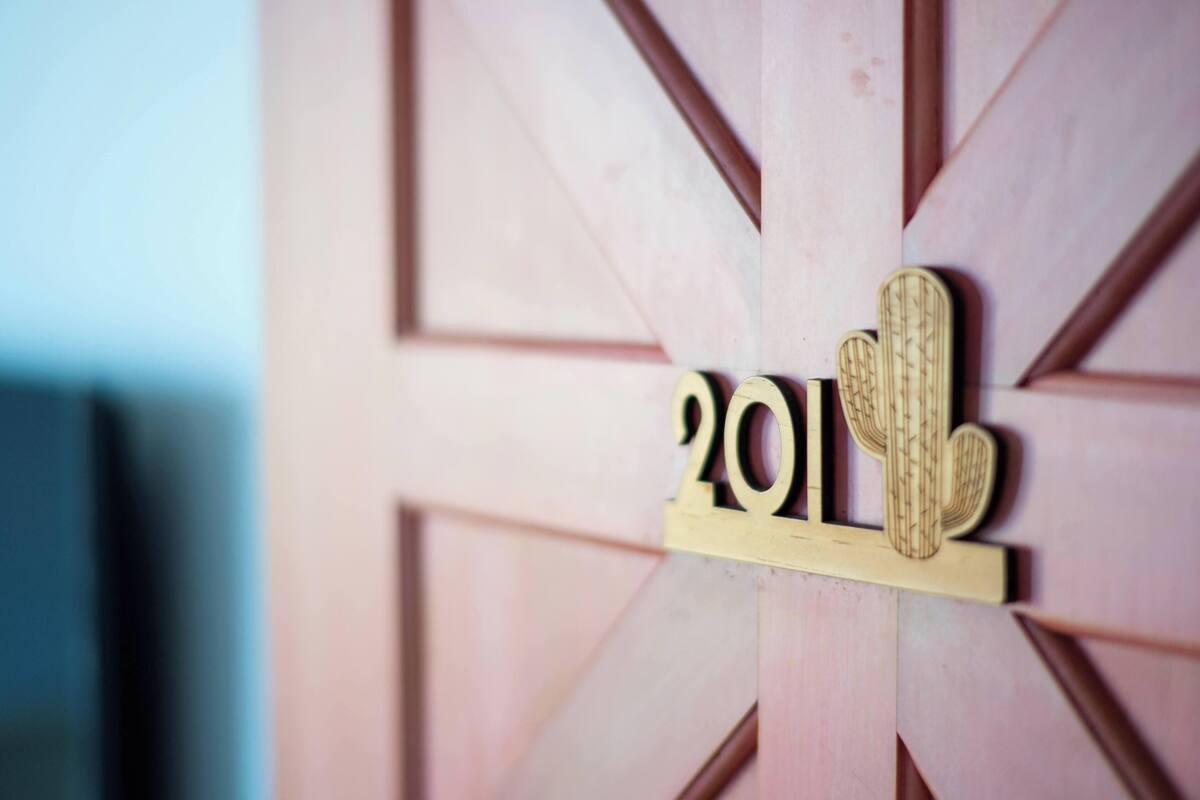 A wooden door with a geometric pattern and a metal plaque with the number '201' and a cactus design.
