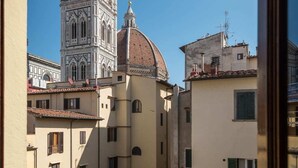 A view of a historic building with a prominent tower and dome, surrounded by traditional buildings with terracotta roofs. - Charming 2bed Apt Overlooking Duomo (Florence)