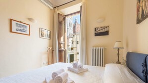 A hotel room with a bed, towels, a lamp, and framed pictures on the walls. - Charming 2bed Apt Overlooking Duomo (Florence)
