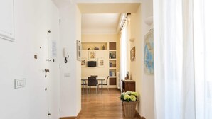 A hallway with wooden flooring, a dining area with chairs and a table, and a wall with framed pictures and a map. - Charming 2bed Apt Overlooking Duomo (Florence)