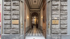 A stone building entrance with a checkered floor, a plaque indicating medical services, and a door with a brass handle. - Charming 2bed Apt Overlooking Duomo (Florence)