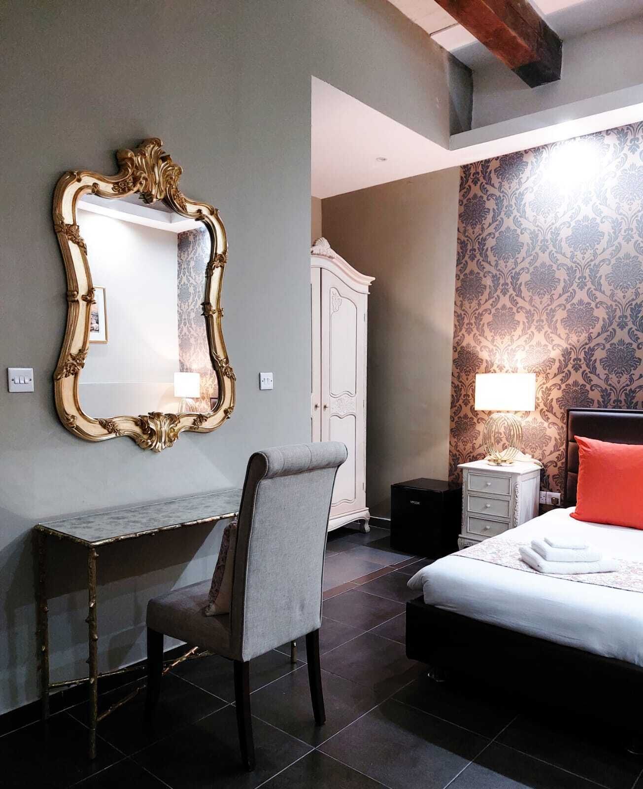 Un dormitorio con cama, escritorio, silla, armario y espejo.