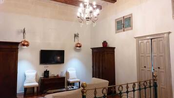 A bedroom with a bed, a TV, a chandelier, and a wardrobe.