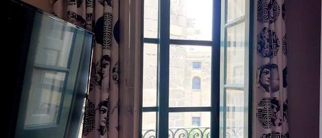 A room with a large window, striped curtains, and a flat-screen TV.