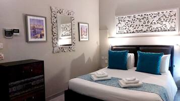 Un dormitorio con cama, dos mesitas de noche, cómoda y decoración mural.