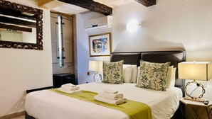 A hotel room with a bed, bedside lamps, a mirror, an air conditioning unit, and a framed picture on the wall. - Casa Birmula (Cospicua)