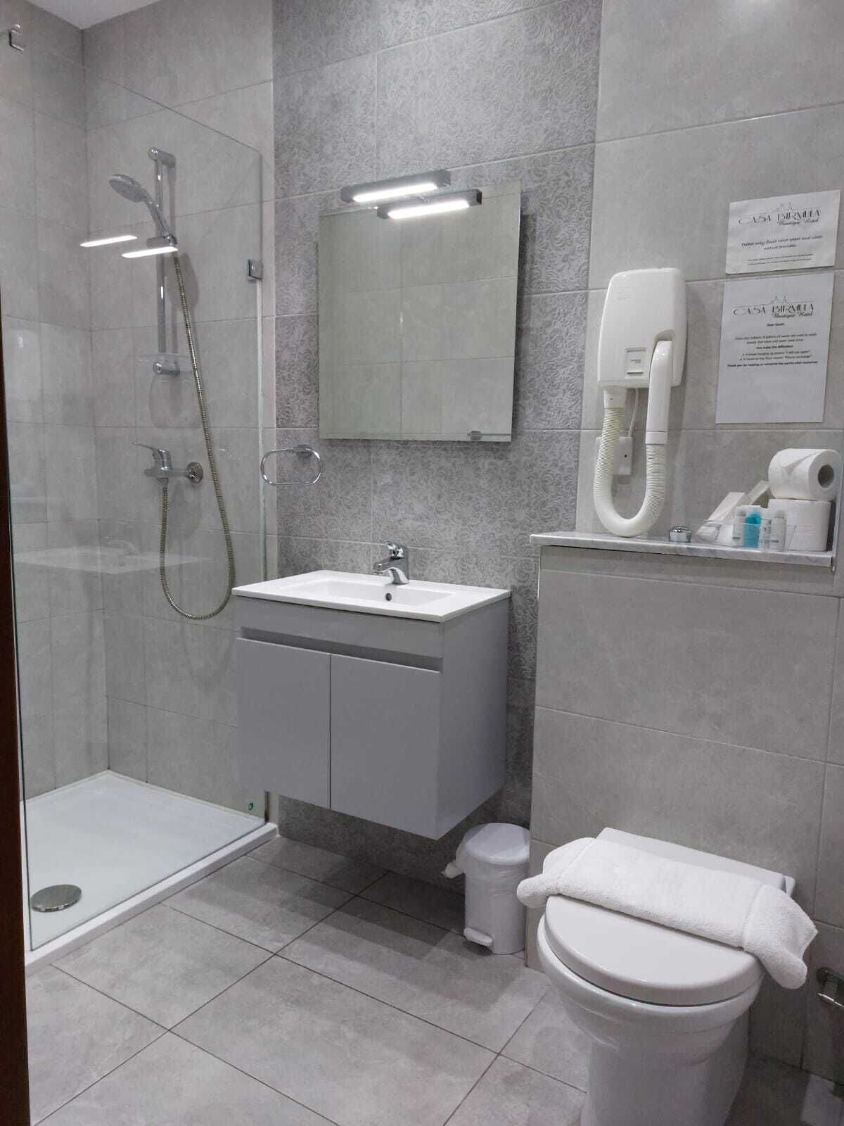 A modern bathroom with a glass-enclosed shower, a white sink, a toilet, and a mirror above the sink.