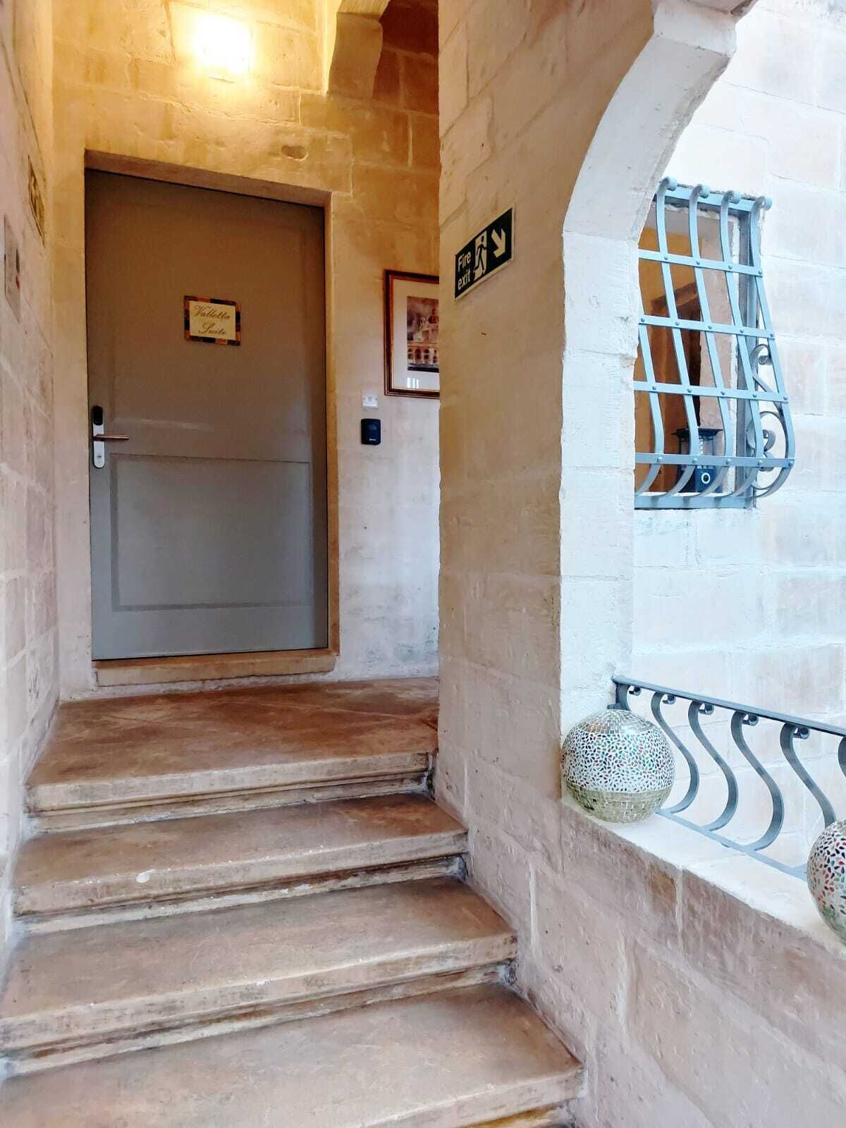 Una escalera de piedra que lleva a una puerta con un cartel de salida de incendios encima.