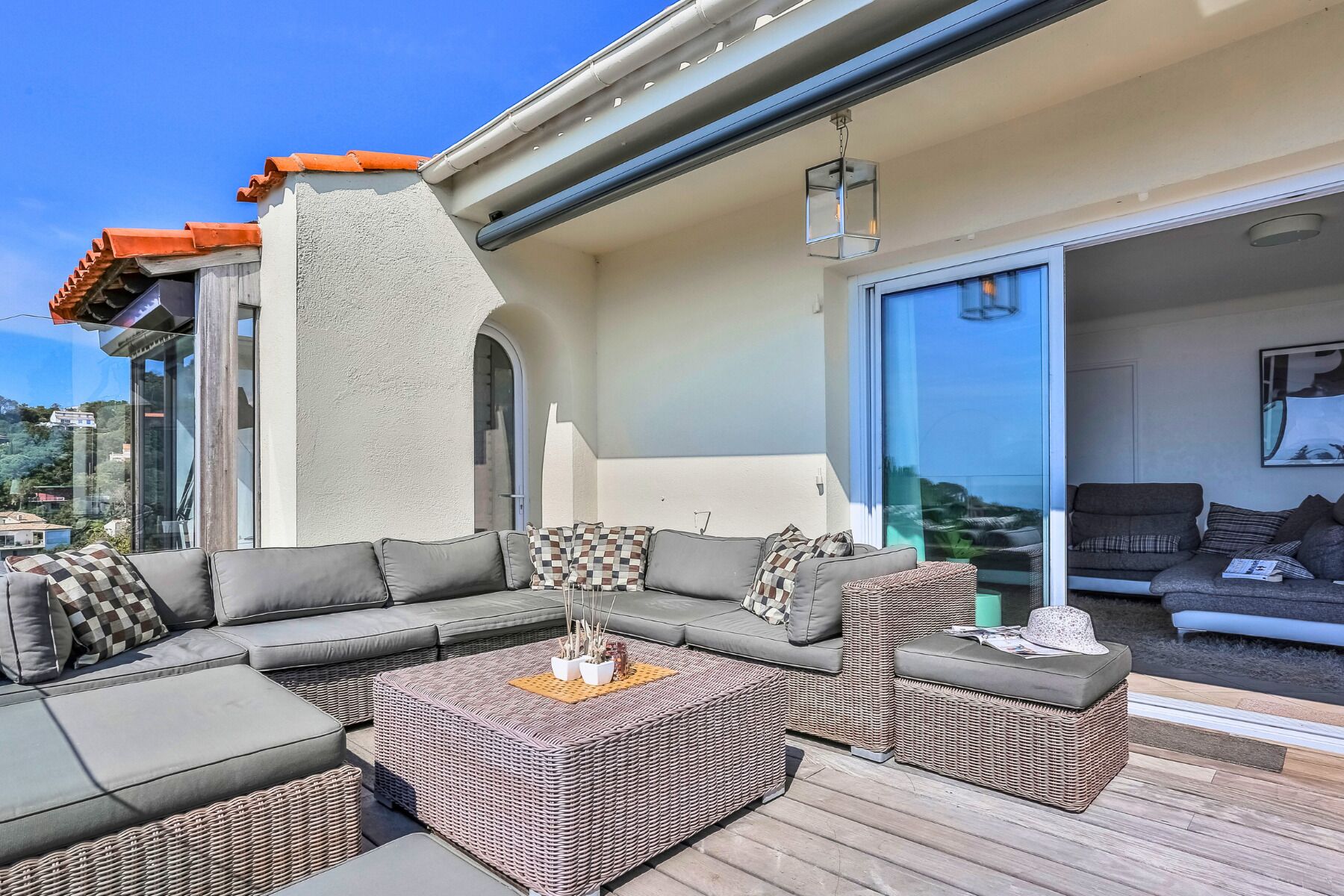 An outdoor living area with a sectional sofa, wicker ottomans, and a fire pit.
