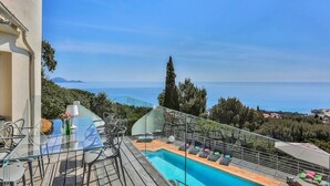 Ein Poolbereich mit Glastisch und Stühlen sowie Blick auf das Meer.