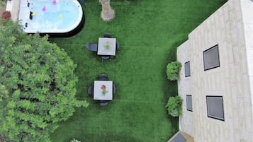 A rooftop garden with a hot tub, two tables with chairs, and a small pool.