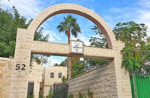 A stone archway with a sign for the 'Finca' hotel, a number '52' on the wall, and a gated entrance. - La Finca - Luxury Suites Hotel (Beersheba)
