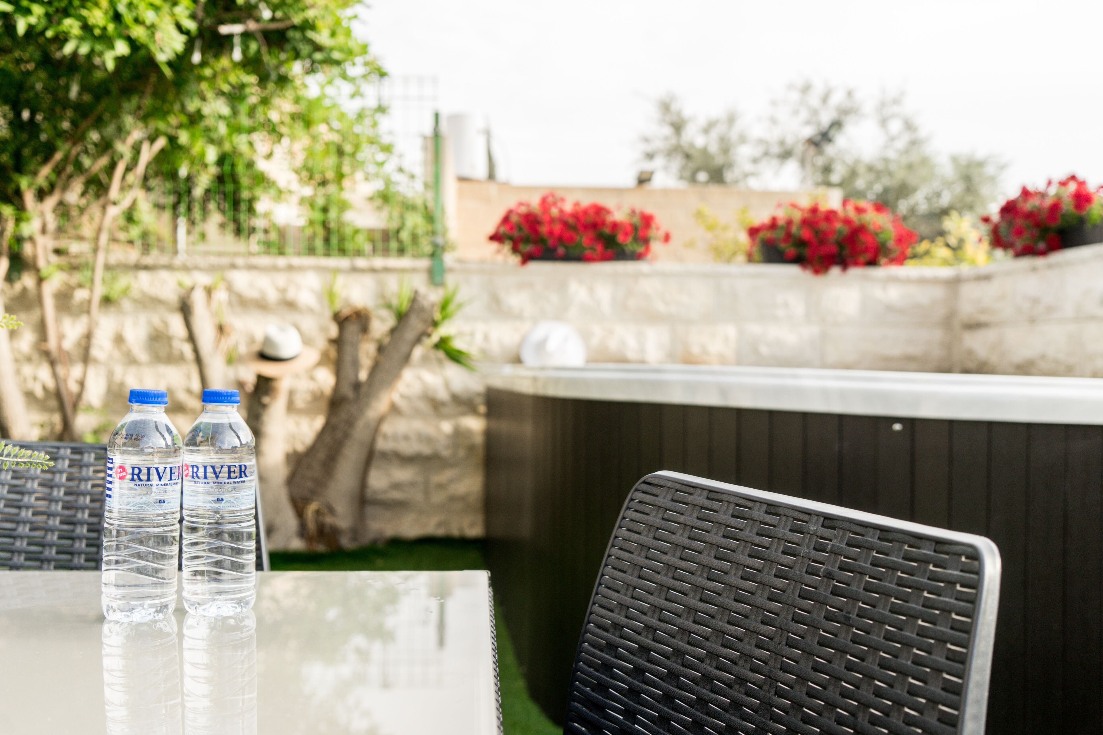 Una mesa con dos botellas de agua y una silla de mimbre.