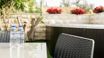A table with two bottles of water and a wicker chair.