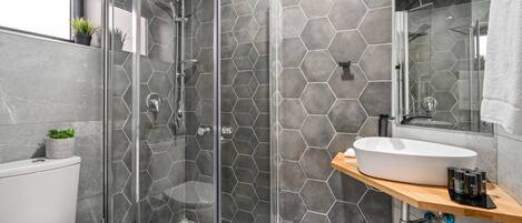 A modern bathroom with a glass-enclosed shower, a white toilet, and a vanity with a large sink.