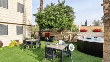 Un patio con mesa y sillas, un jacuzzi y un árbol.