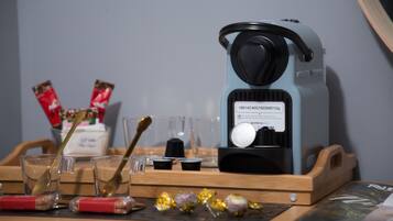 Máquina de café sobre bandeja de madeira, com xícaras, colher e algumas barras de chocolate.