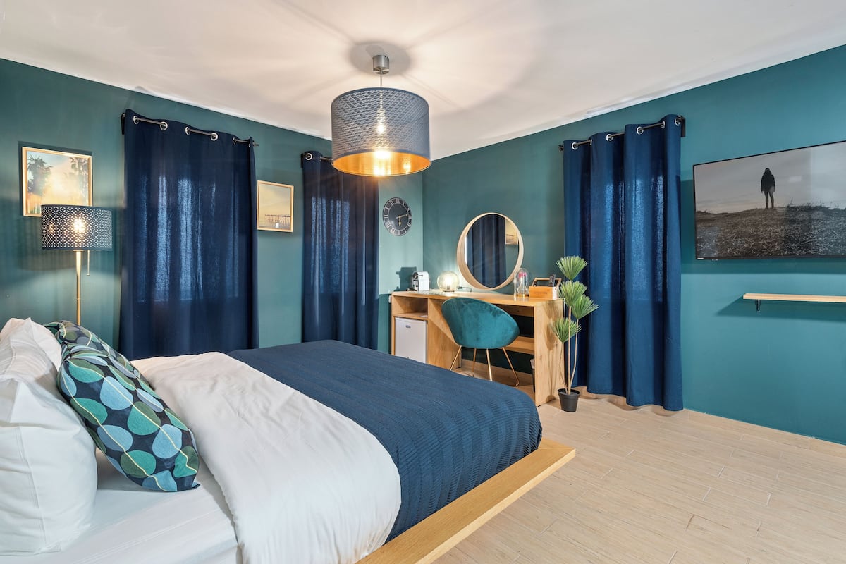 A bedroom with a bed, desk, chair, and a large mirror.