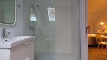Een moderne badkamer met een glazen douchecabine, een witte wastafel en een spiegel.