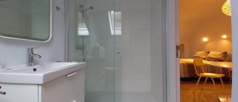 Une salle de bain moderne avec une douche à parois de verre, un lavabo blanc et un miroir.