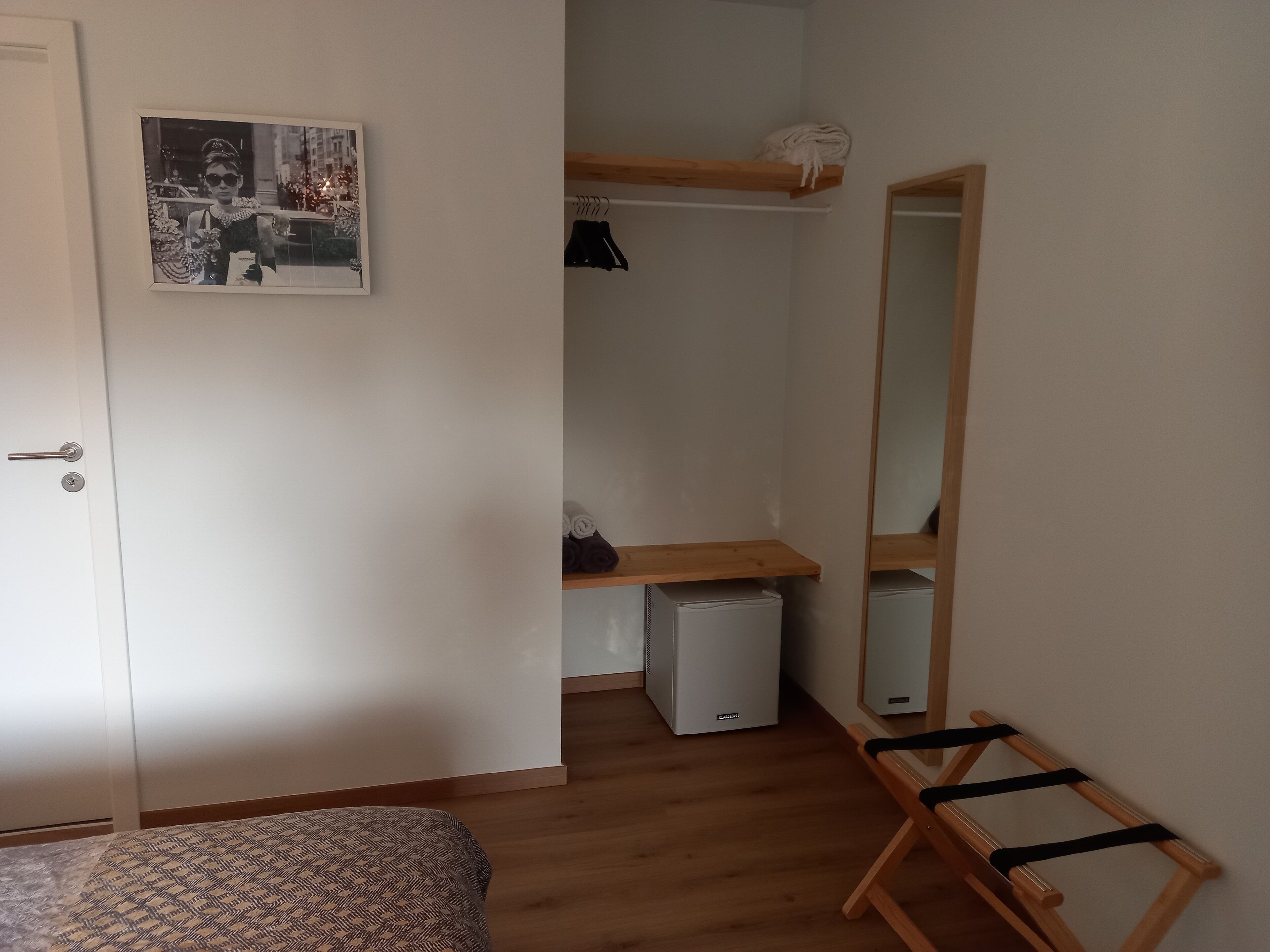 Een slaapkamer met een bed, een kledingkast, een spiegel en een kleine verwarming.