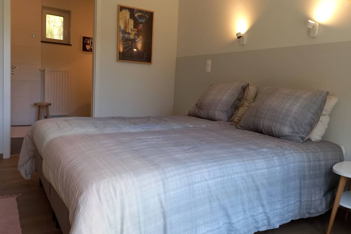 Un dormitorio con una cama grande, dos luces fijadas a la pared, un radiador y un cuadro enmarcado.