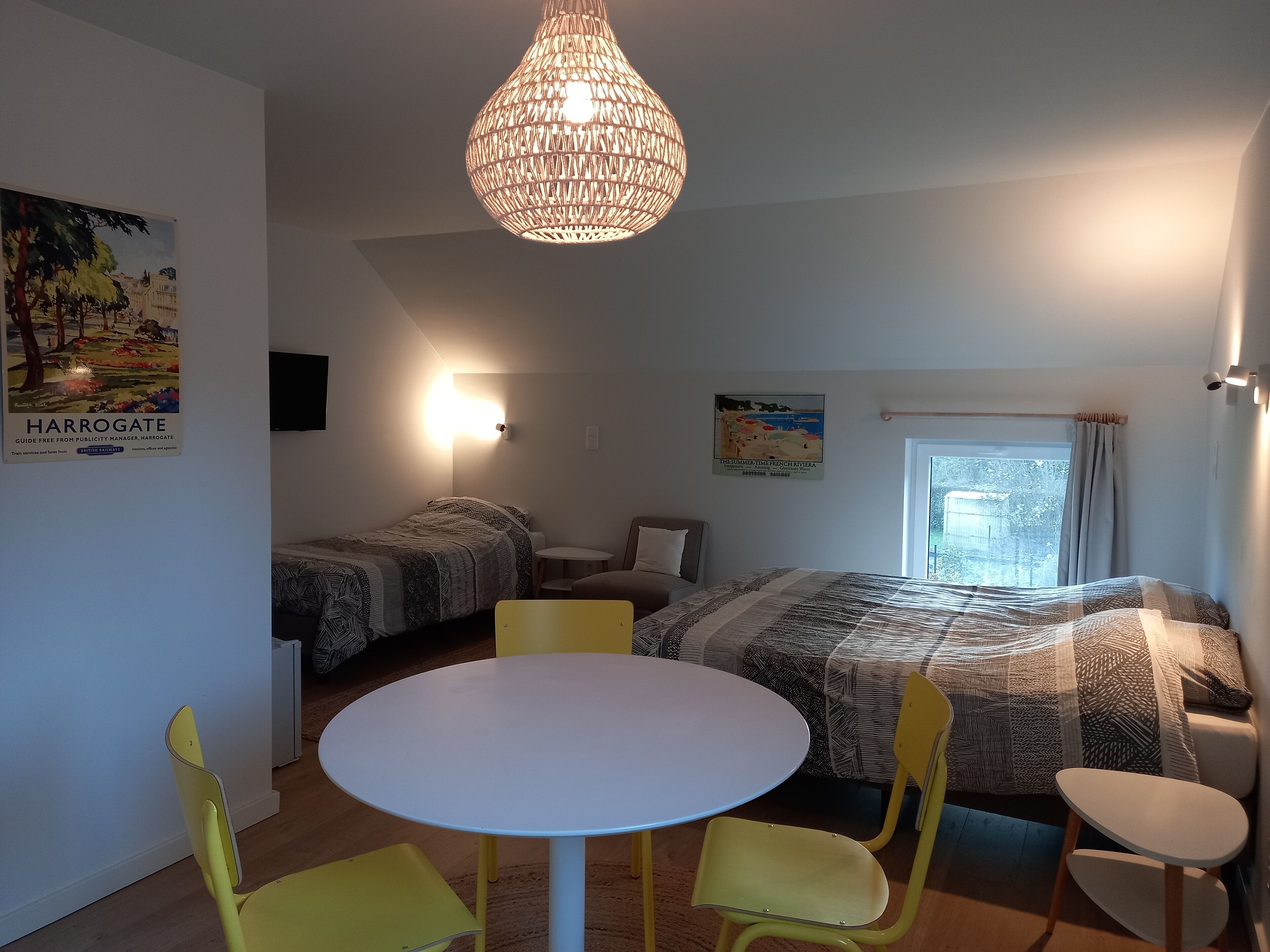 Een kamer met twee bedden, een ronde tafel en gele stoelen.
