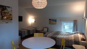 Een kamer met twee bedden, een ronde tafel en gele stoelen.