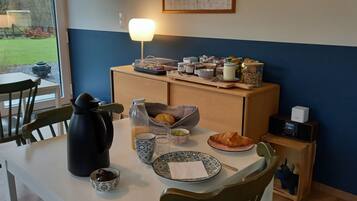 Une table de petit-déjeuner avec une machine à café, des croissants et divers autres aliments pour le petit-déjeuner.