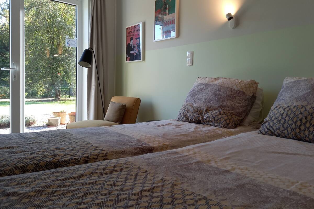 Un dormitorio con dos camas, una ventana con cortinas y cuadros colgados en la pared.