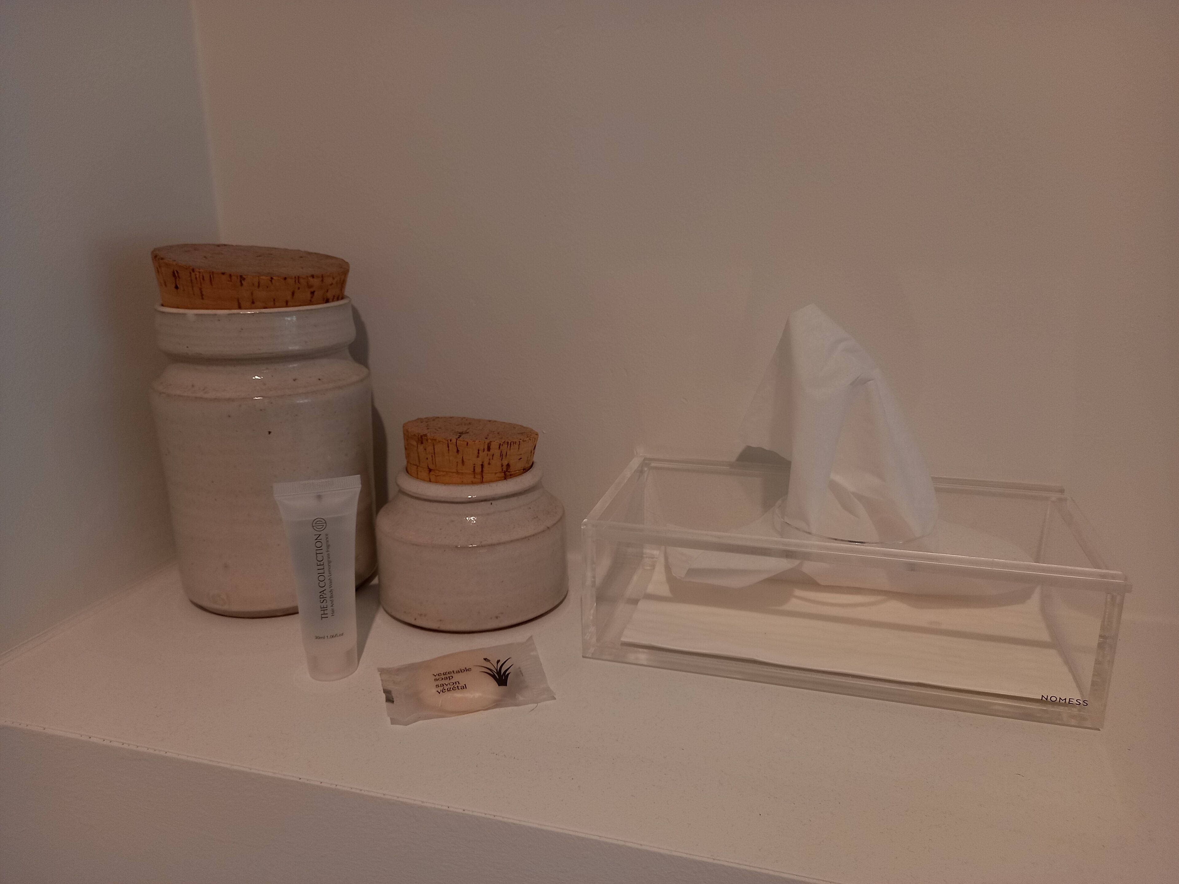 A shelf with three jars, a tissue box, and a small packet.