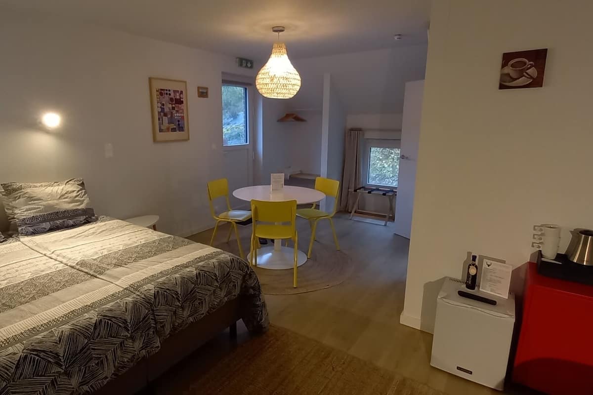 Un dormitorio con una cama grande, un escritorio pequeño, una silla y una cafetera.
