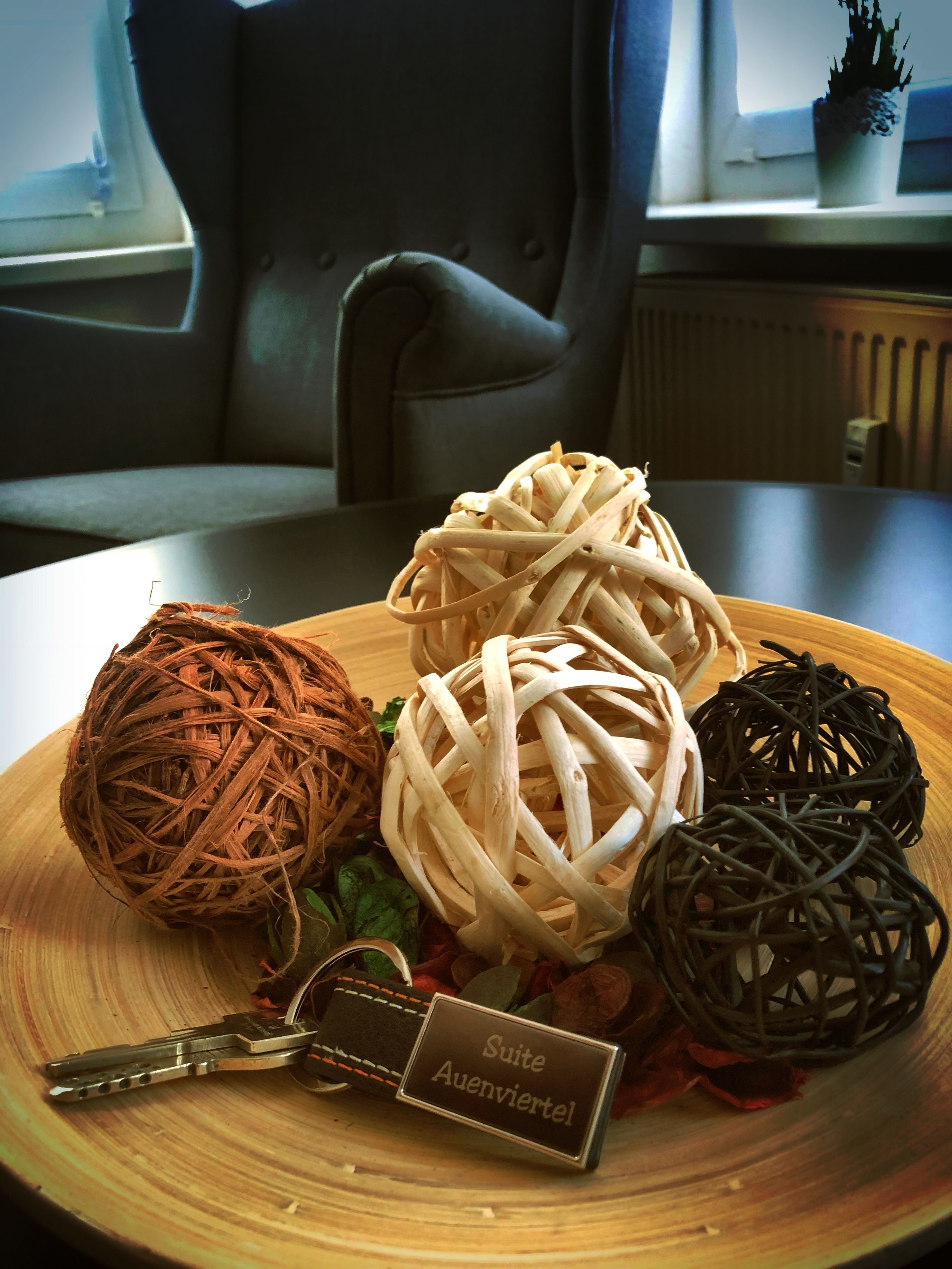 A wooden table with four woven balls and a keychain with a name tag.