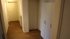 A narrow hallway with wooden flooring, white walls, and a white door at the end. - Suite Auenviertel (Erfurt)