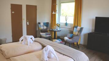 Een hotelkamer met twee bedden, een televisie, een klein tafeltje met een vaas en twee stoelen.