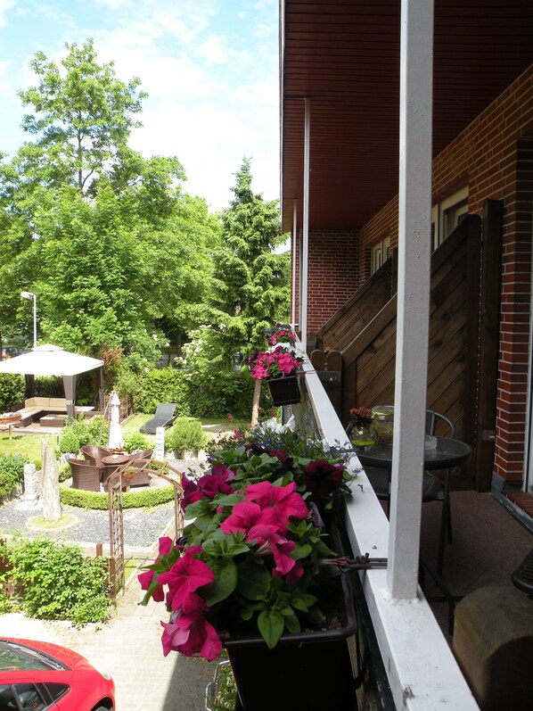 Varanda com vasos de plantas, móveis de exterior e vista para um jardim e árvores.