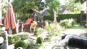 A garden with a slide, outdoor furniture, and a pond. - Hotel Garni Kröger (Wittmund)