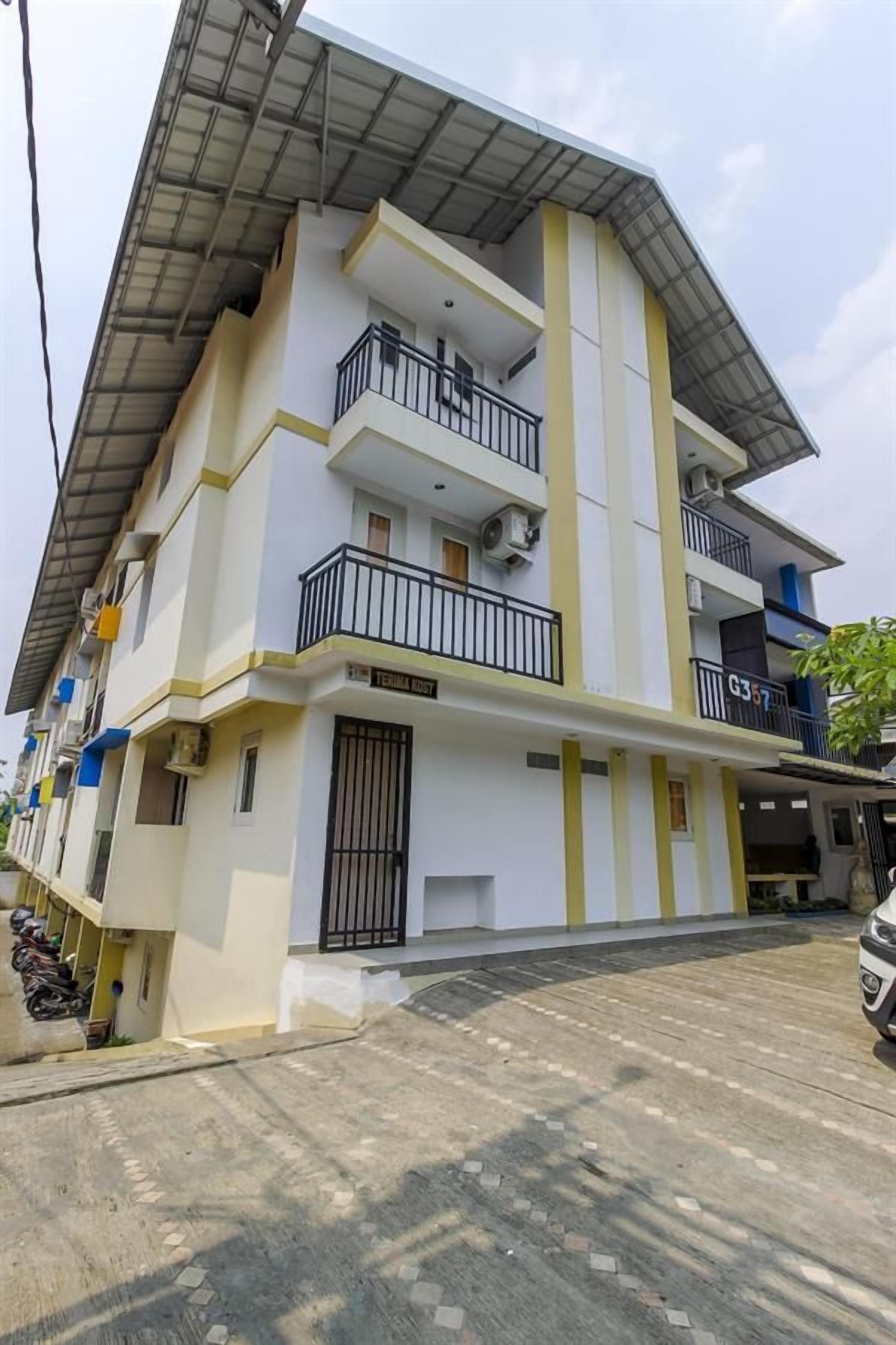 Um edifício residencial de vários andares, com varandas, entrada fechada por portão e área de estacionamento coberta.