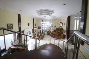 A hotel lobby with a staircase, seating area, and a reception desk. - RedDoorz @ Cibogo Puncak Bogor (Megamendung)