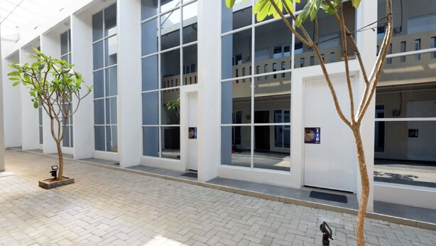 A modern building with large windows and a paved walkway. - RedDoorz Plus near Paragon Mall Semarang (Semarang)