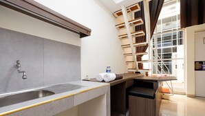 A modern kitchen with a built-in sink, a wooden countertop, and a window with a view of the outside. - RedDoorz Plus near Paragon Mall Semarang (Semarang)