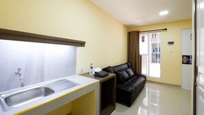 A compact kitchen with a sink, a small countertop, and a black leather sofa. - RedDoorz Plus near Paragon Mall Semarang (Semarang)