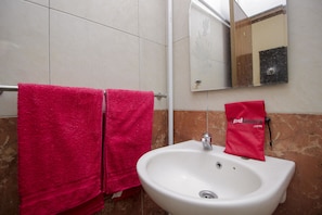 A bathroom with a white sink, a mirror, and two pink towels hanging on a metal towel rack.