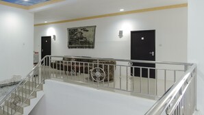 Un hall d’hôtel avec un escalier, un grand tableau et deux portes.
