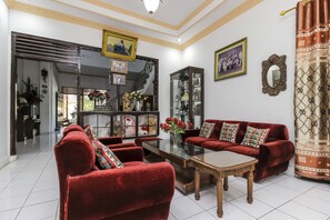 A living room with red sofas, a glass coffee table, and a staircase leading to another level. - RedDoorz near Sam Ratulangi Airport (Manado)