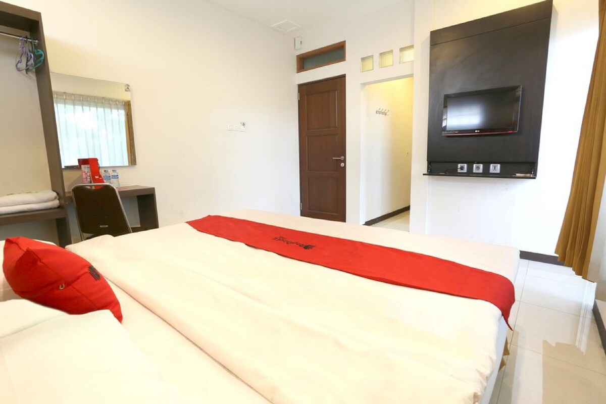 Une chambre d’hôtel avec un lit, un bureau, une télévision et une porte.