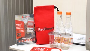 Una mesa con una bolsa promocional de RedDoorz, dos botellas de agua, una lata y un menú.