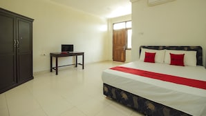 Una habitación de hotel con cama, escritorio, armario y puerta.